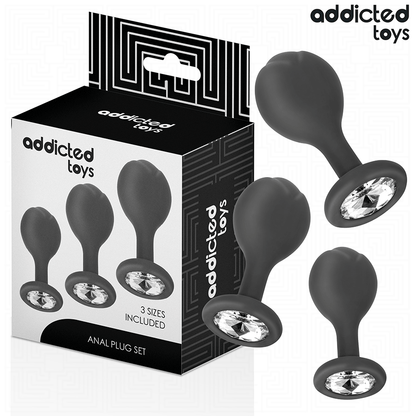 Kit de 3 Plugs Anais de Metal Addicted Toys: Fotografia comercial sofisticada exibindo os três plugs de alumínio médico alinhados por ordem crescente de tamanho (S, M e L), destacando o acabamento espelhado e os cristais brilhantes nas bases.