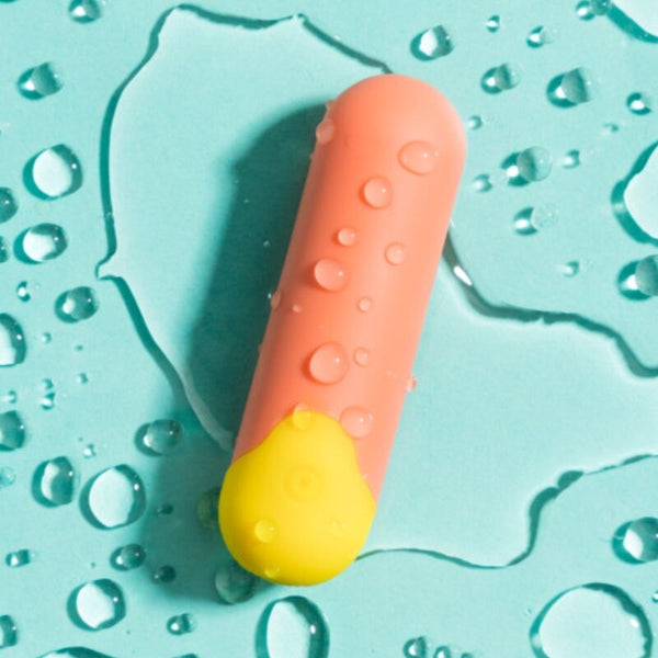 Vibrador Bala ROMP Riot: Estimulador multifuncional nas cores laranja e amarelo exibido montado com o seu cordão de segurança estendido.